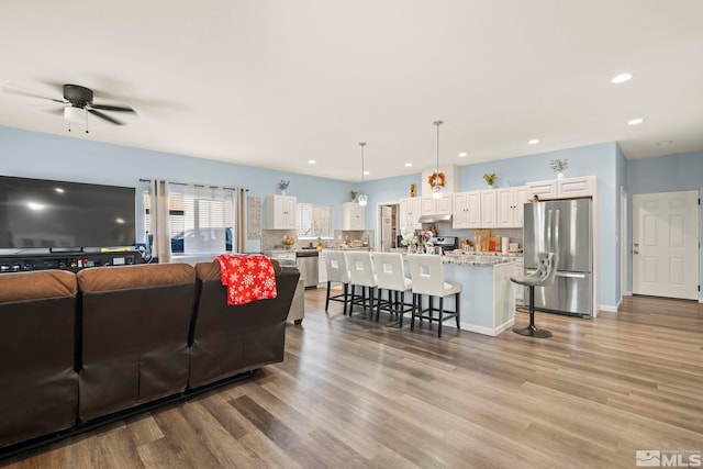 living room featuring light wood-type flooring and ceiling fan