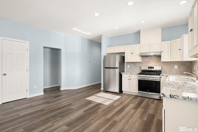 kitchen with light stone countertops, stainless steel appliances, sink, backsplash, and dark hardwood / wood-style floors