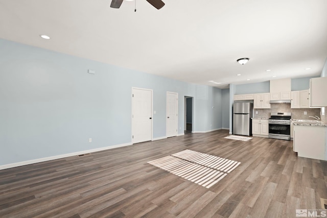 unfurnished living room featuring ceiling fan, sink, and wood-type flooring