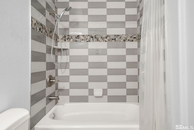 bathroom with toilet and tiled shower / bath