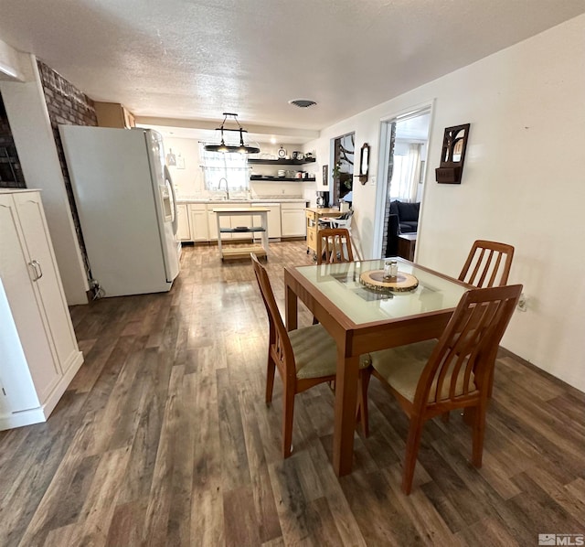 dining space featuring a textured ceiling, sink, and dark hardwood / wood-style floors