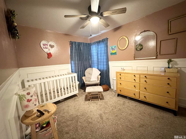 carpeted bedroom with a nursery area and ceiling fan