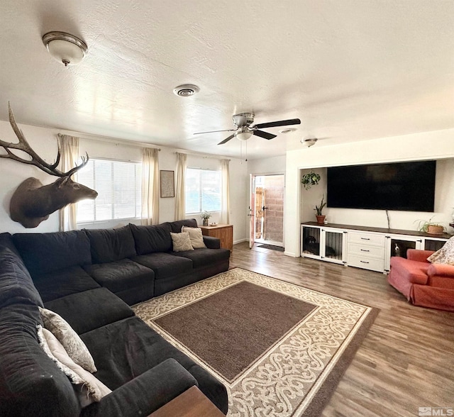 living room featuring a textured ceiling, wood-type flooring, and ceiling fan