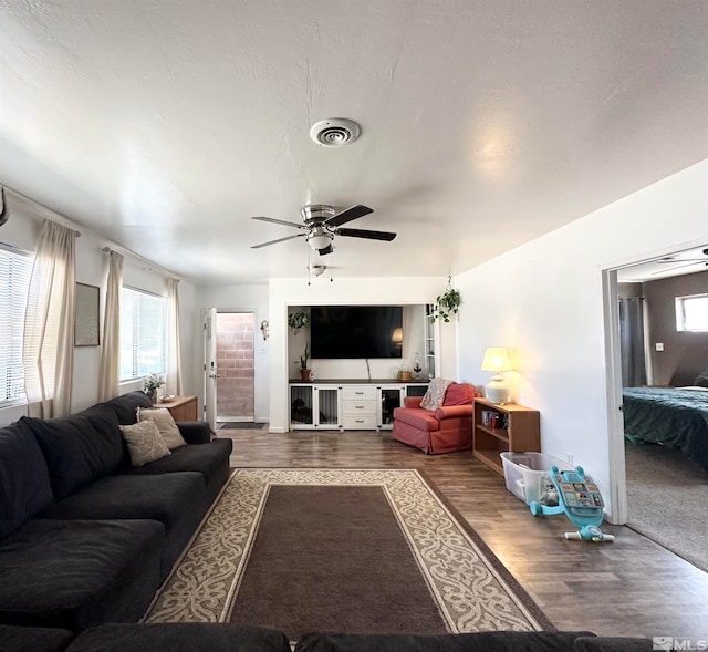 living room featuring dark wood-type flooring and ceiling fan