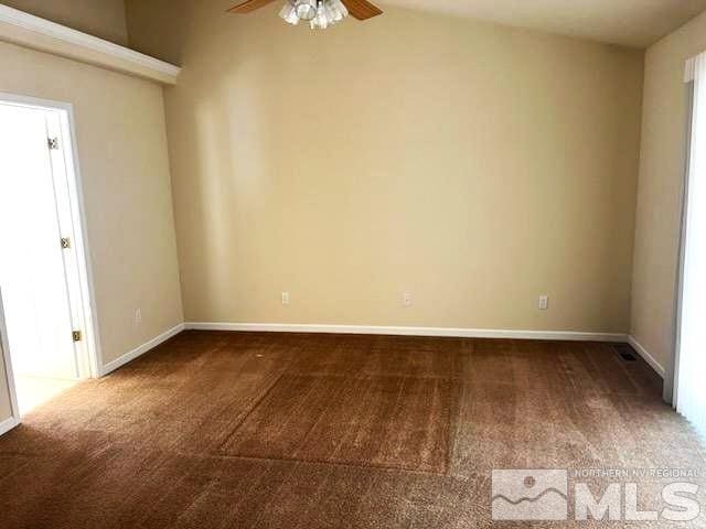 spare room with ceiling fan, dark carpet, and vaulted ceiling