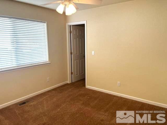 empty room with ceiling fan and dark carpet