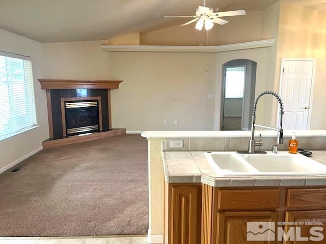 kitchen featuring sink, vaulted ceiling, ceiling fan, tile counters, and light colored carpet