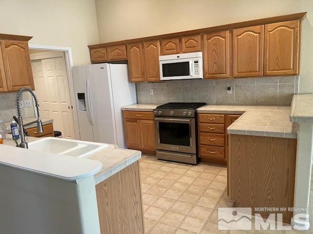 kitchen with backsplash, kitchen peninsula, white appliances, and sink