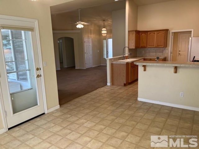 kitchen with kitchen peninsula, a kitchen breakfast bar, sink, tile countertops, and white fridge