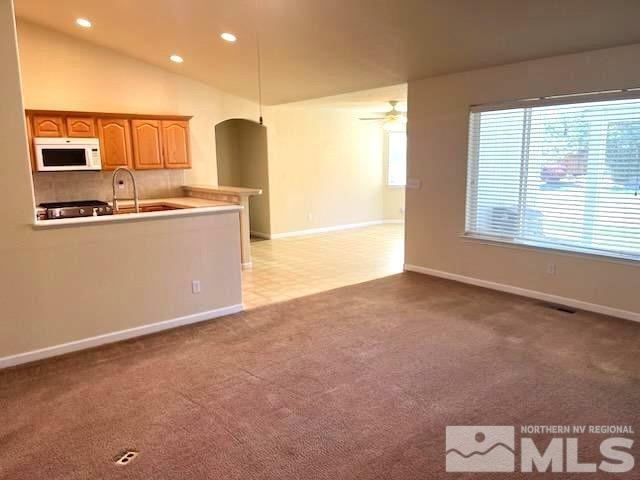 kitchen featuring ceiling fan, light colored carpet, and vaulted ceiling