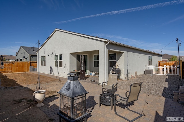 back of property with an outdoor fire pit and a patio