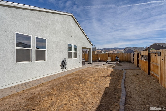 view of home's exterior with a mountain view and a patio area