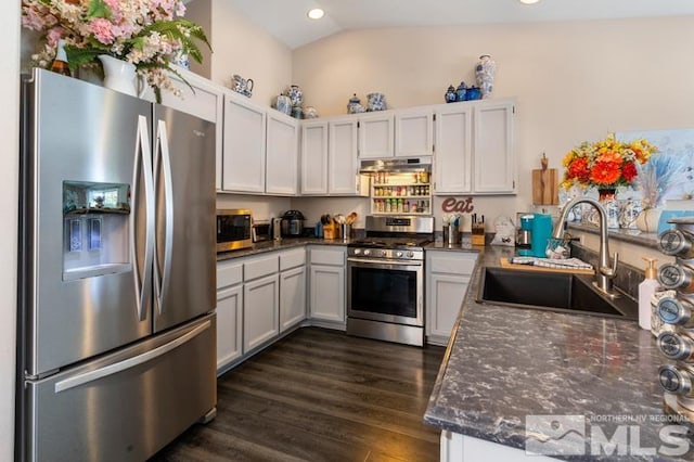 kitchen with lofted ceiling, sink, appliances with stainless steel finishes, and white cabinets