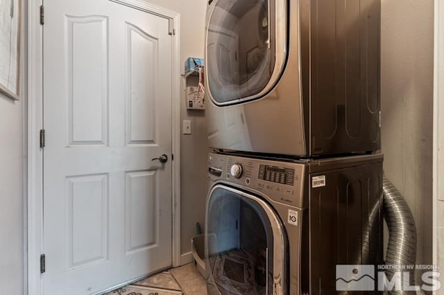 laundry area featuring stacked washer / drying machine and light tile patterned flooring