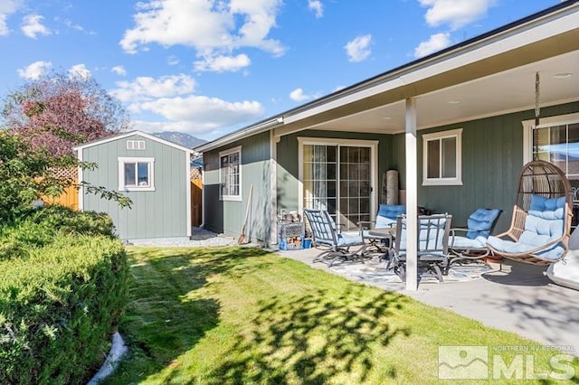 back of house with a patio area, a storage unit, and a lawn