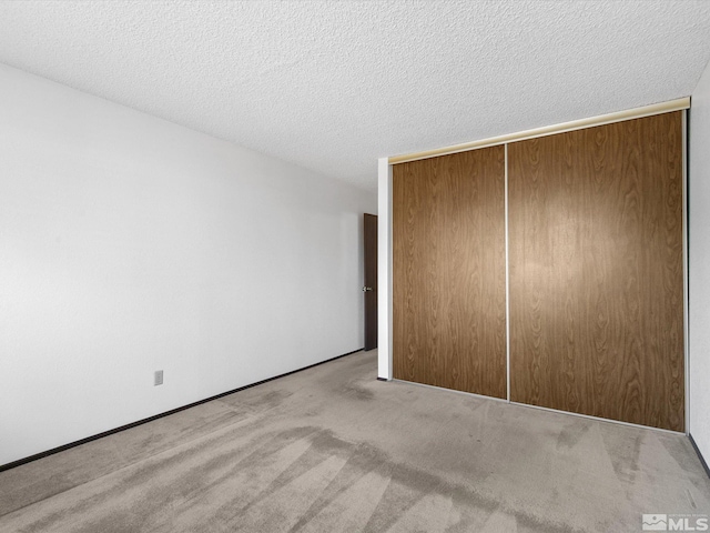 unfurnished bedroom featuring a closet, light colored carpet, and a textured ceiling