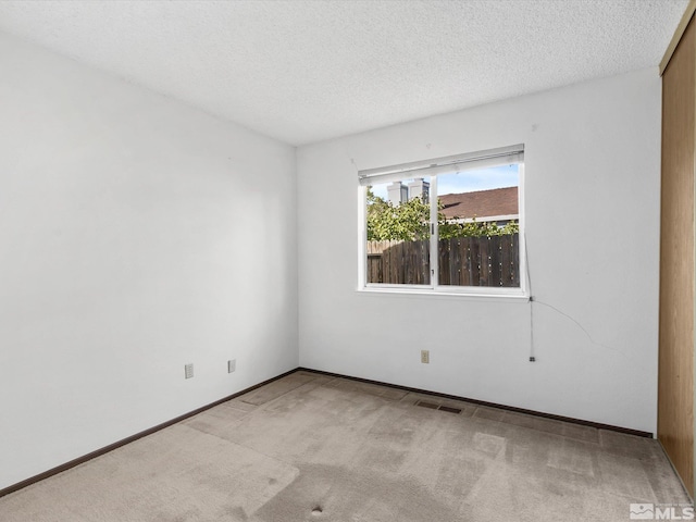 carpeted spare room with a textured ceiling