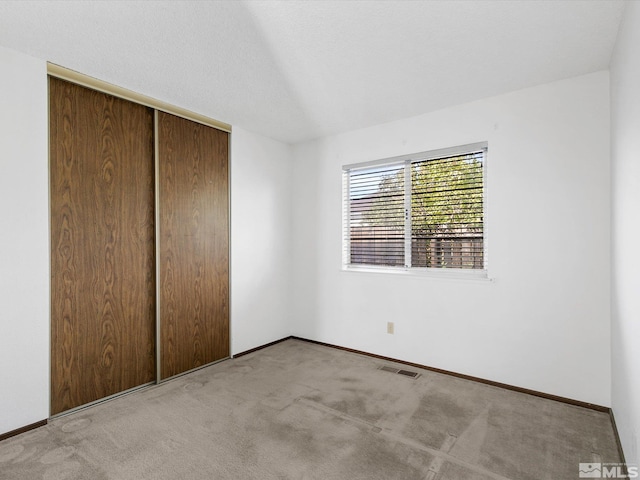 unfurnished bedroom with light colored carpet and a closet