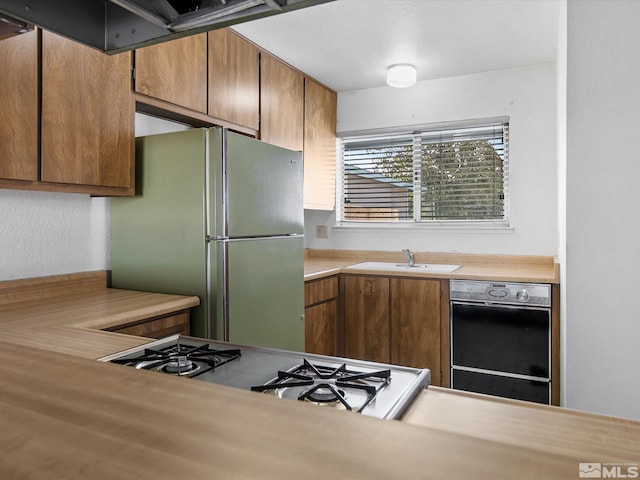 kitchen featuring dishwasher, stainless steel fridge, gas range gas stove, and sink