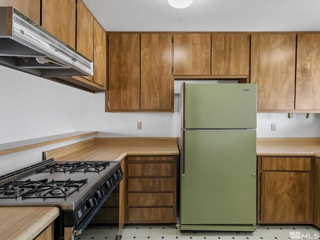 kitchen featuring black gas stove, stainless steel refrigerator, and extractor fan