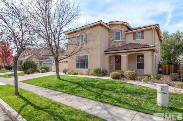 mediterranean / spanish home featuring a garage and a front lawn