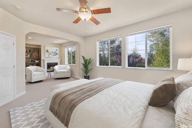 carpeted bedroom featuring multiple windows and ceiling fan