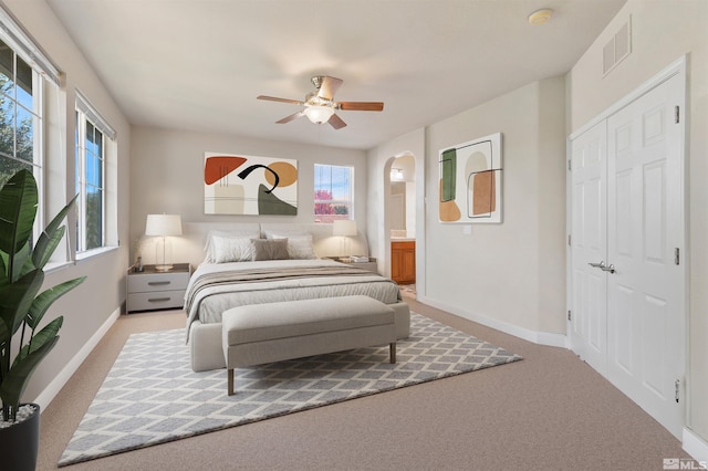 carpeted bedroom featuring ensuite bath, a closet, and ceiling fan