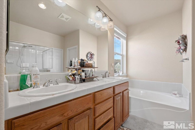 bathroom with vanity and shower with separate bathtub