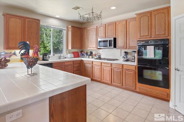 kitchen with black appliances, sink, kitchen peninsula, tile counters, and light tile patterned floors