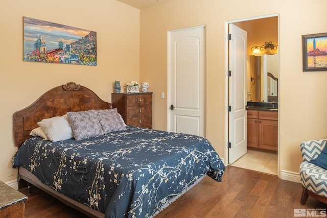 bedroom with hardwood / wood-style floors, ensuite bath, and sink