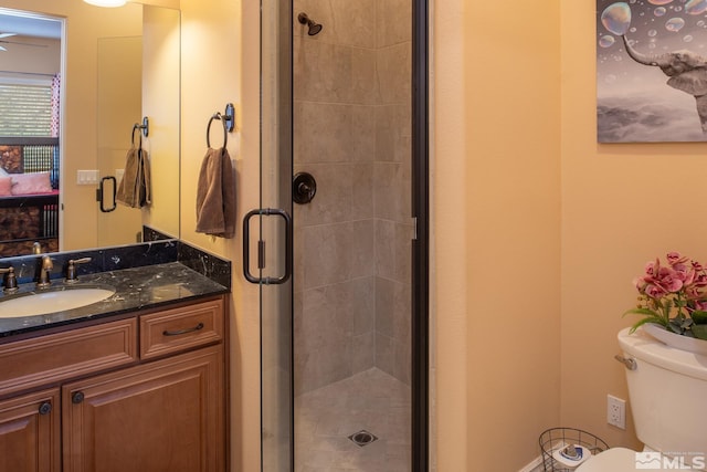 bathroom with a shower with door, vanity, and toilet