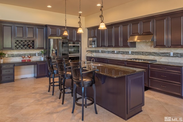 kitchen featuring dark brown cabinets, a center island with sink, sink, decorative light fixtures, and appliances with stainless steel finishes