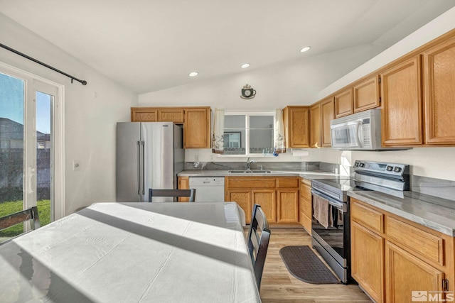 kitchen with sink, vaulted ceiling, appliances with stainless steel finishes, and light wood-type flooring