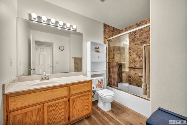 full bathroom featuring vanity, toilet, wood-type flooring, and bath / shower combo with glass door