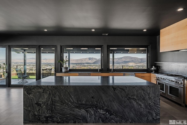 kitchen featuring a center island, a mountain view, range with two ovens, and dark stone counters