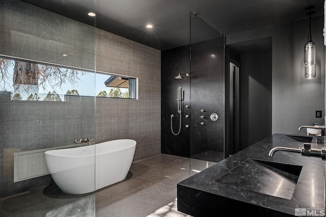 bathroom featuring tile walls, separate shower and tub, sink, and tile patterned flooring