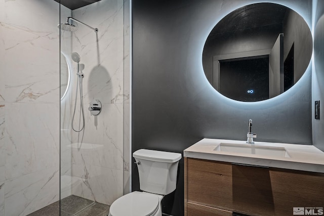 bathroom featuring vanity, a tile shower, and toilet