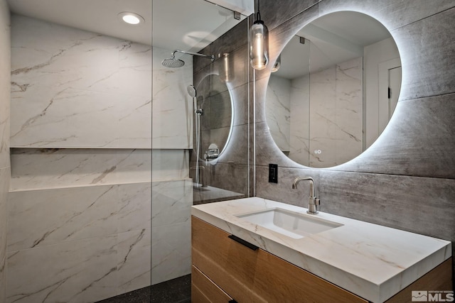 bathroom with vanity, tasteful backsplash, tile walls, and tiled shower