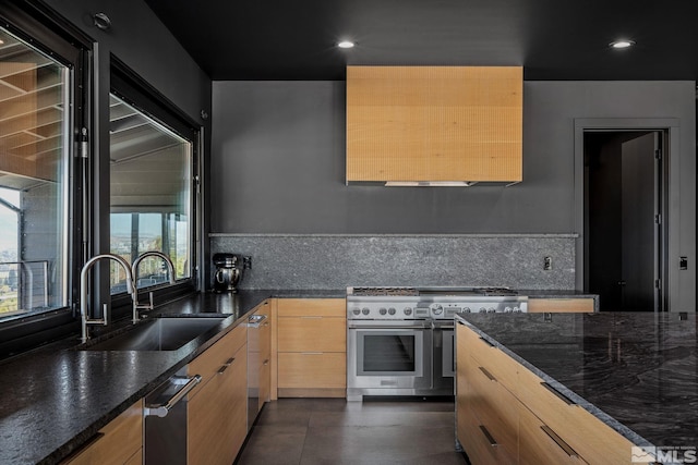 kitchen with light brown cabinetry, appliances with stainless steel finishes, sink, backsplash, and dark stone counters