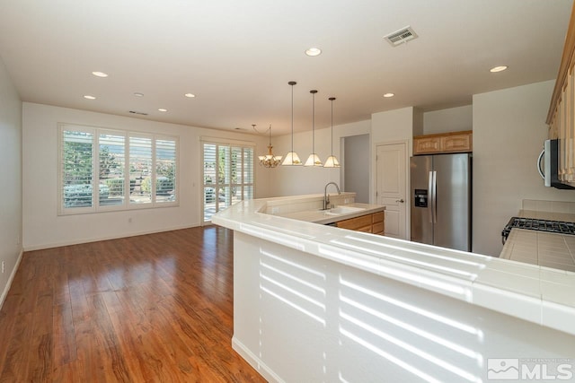 kitchen featuring appliances with stainless steel finishes, sink, dark hardwood / wood-style flooring, hanging light fixtures, and a chandelier