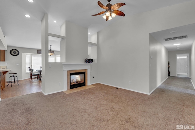 unfurnished living room featuring vaulted ceiling, light carpet, a tiled fireplace, and ceiling fan