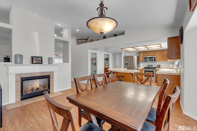 dining space with lofted ceiling, sink, a fireplace, and light wood-type flooring