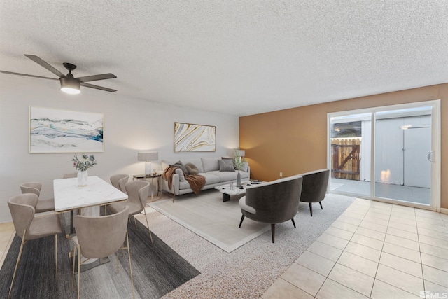 living room with ceiling fan, a textured ceiling, and light tile patterned flooring