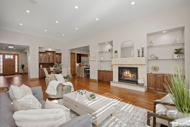 living room with a premium fireplace, hardwood / wood-style flooring, and built in shelves