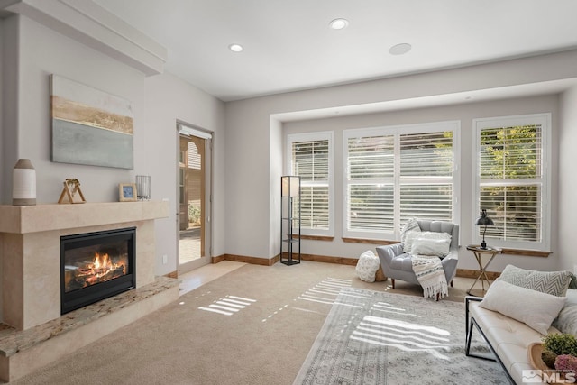 living area with light carpet and a high end fireplace