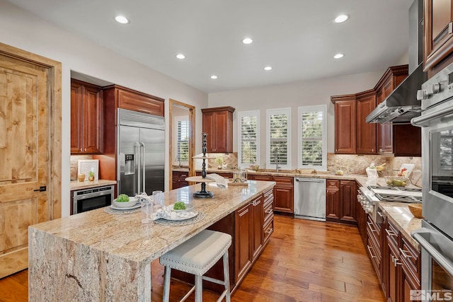 kitchen with light stone countertops, appliances with stainless steel finishes, a center island, hardwood / wood-style floors, and a breakfast bar area