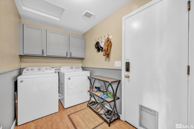 laundry room featuring cabinets, separate washer and dryer, and light wood-type flooring