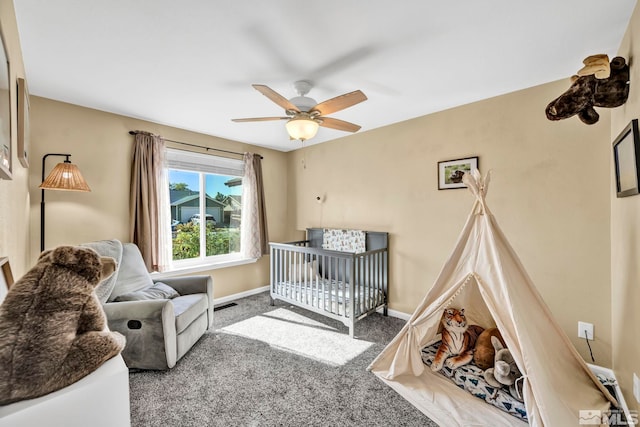 carpeted bedroom featuring a crib and ceiling fan