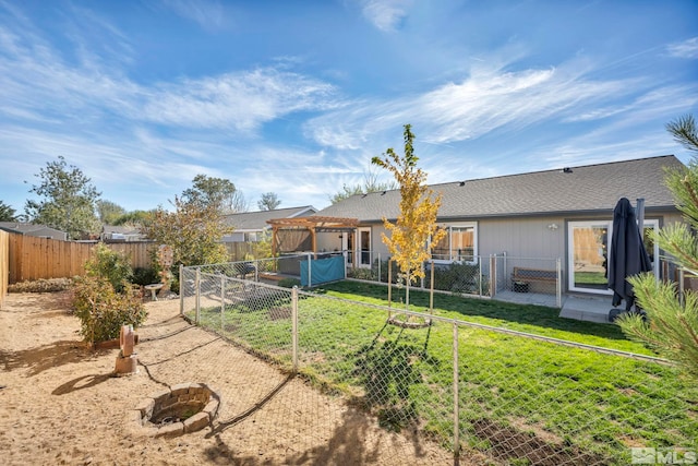 rear view of house featuring a yard and an outdoor fire pit