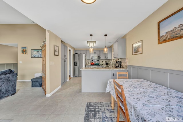 kitchen featuring kitchen peninsula, tasteful backsplash, hanging light fixtures, gray cabinets, and stainless steel appliances